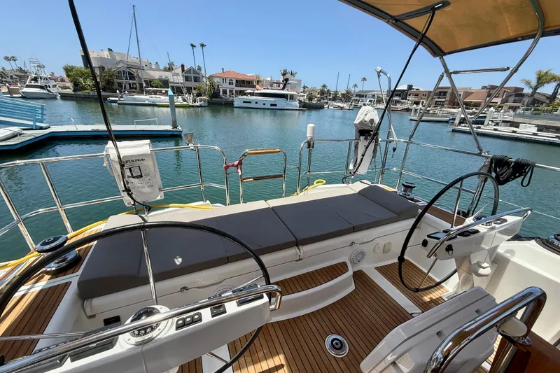 Slide: The Image of Cockpit view of 2018 Jeanneau 58 yacht in a marina, featuring dual steering wheels. - 38