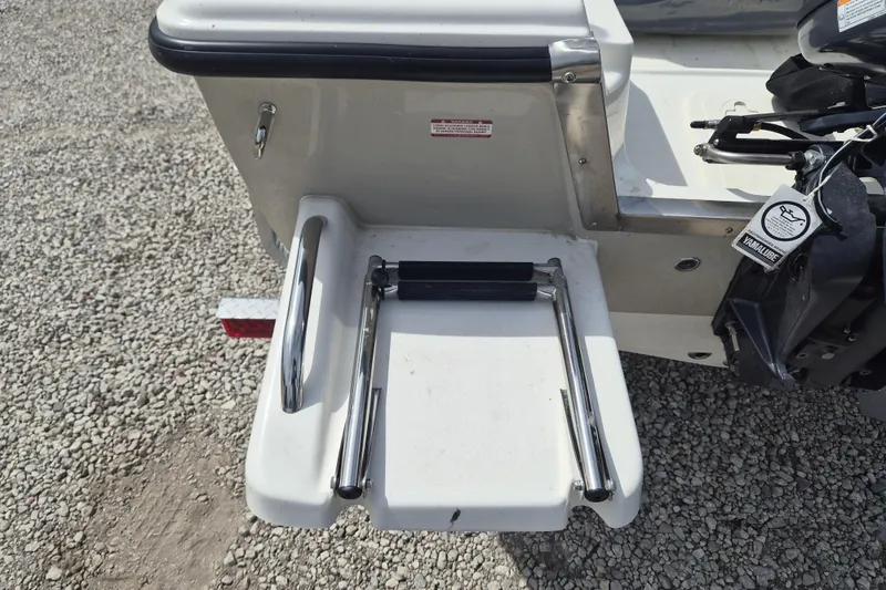 Slide: The Image of 2026 Key West 1720 Center Console boat with a foldable swim ladder on gravel. - 9