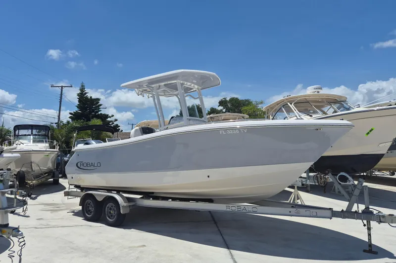 The Image of 2023 Robalo R230 Center Console boat on trailer under clear blue sky. - 1