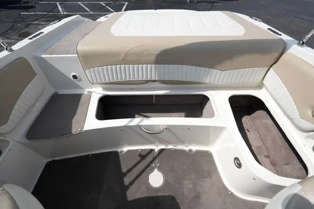 Slide: The Image of 2015 Stingray 208 LR boat interior with beige and white seating, open storage compartments. - 24