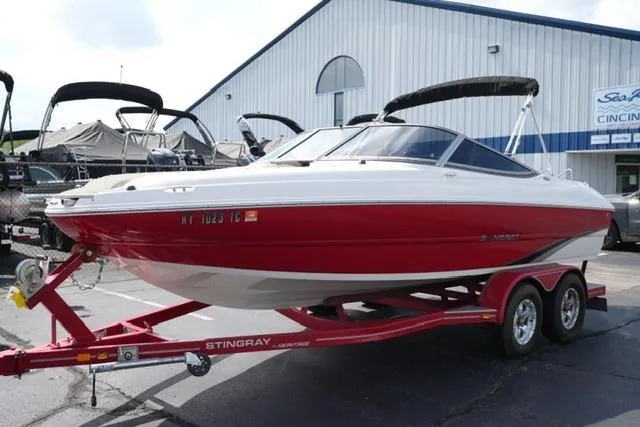 Slide: The Image of 2015 Stingray 208 LR boat on trailer, red and white, parked outside dealership. - 9