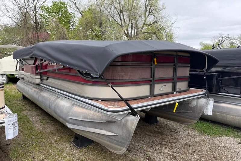 The Image of 2015 Crest Classic 230 SLC pontoon boat with cover, parked on gravel. - 1