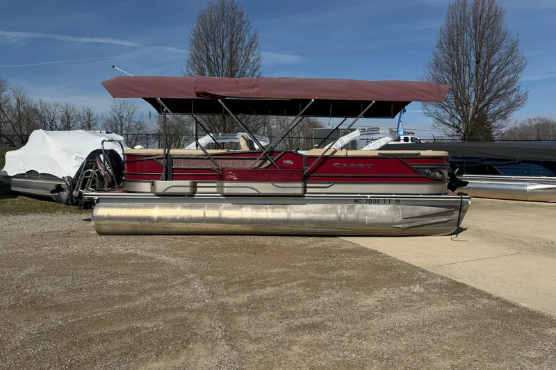 Slide: The Image of 2015 Crest Classic 230 SLC pontoon boat with red canopy, parked outdoors. - 17