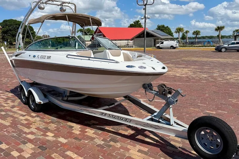 The Image of 2005 Crownline 216 LS boat on trailer, parked on brick pavement under a sunny sky. - 1
