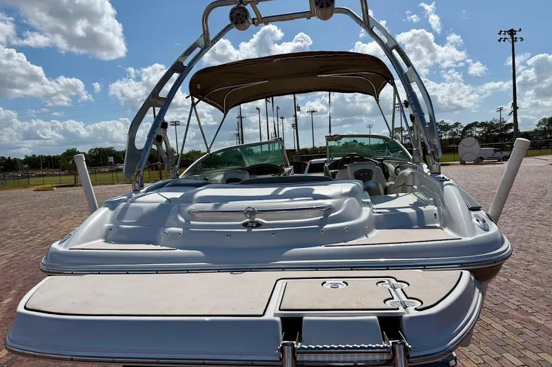Slide: The Image of 2005 Crownline 216 LS boat with canopy, parked on brick pavement under a blue sky. - 11