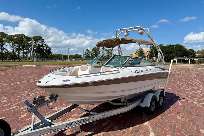Slide: The Image of 2005 Crownline 216 LS boat on trailer, parked on brick pavement under a clear sky. - 4