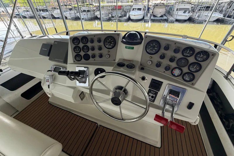 Slide: The Image of 1998 Carver 355 Aft Cabin Motor Yacht helm with gauges and controls, docked at marina. - 11