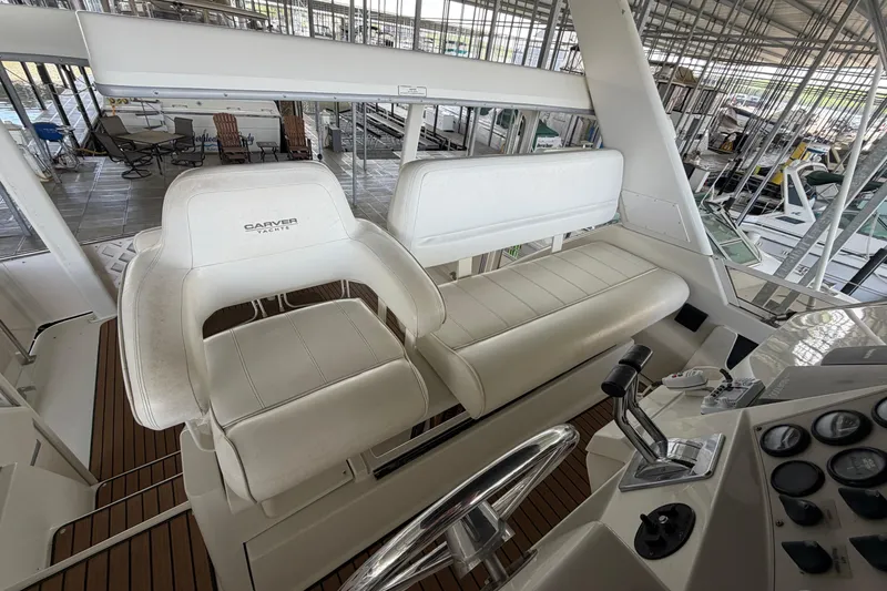 Slide: The Image of 1998 Carver 355 Aft Cabin Motor Yacht helm with white seating and control panel. - 13