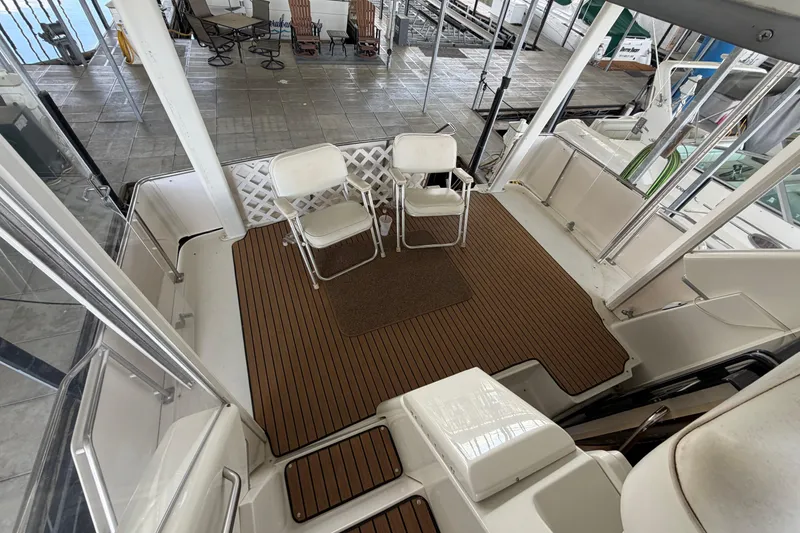 Slide: The Image of 1998 Carver 355 Aft Cabin Motor Yacht deck with chairs and wood flooring. - 14