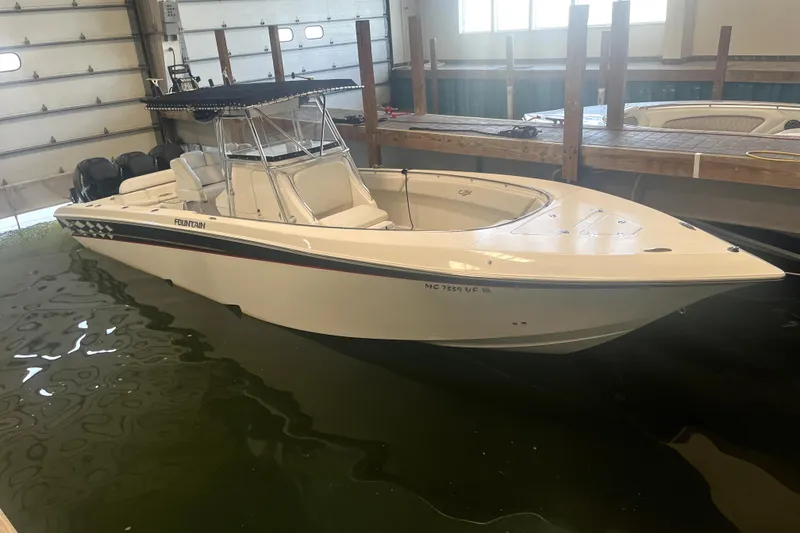 The Image of 2005 Fountain 34 Center Console boat docked indoors, featuring sleek design and twin engines. - 0