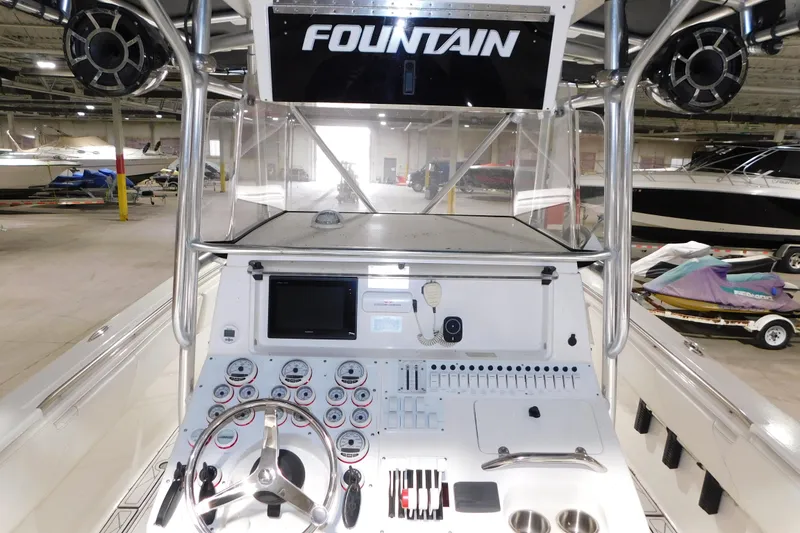 Slide: The Image of 2005 Fountain 34 Center Console boat dashboard with steering wheel and controls in a showroom. - 26