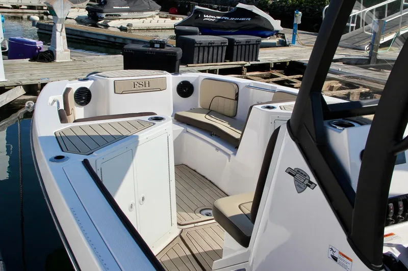 Slide: The Image of 2024 Yamaha Boats 222 FSH Sport E interior with seating and storage at a dock. - 10