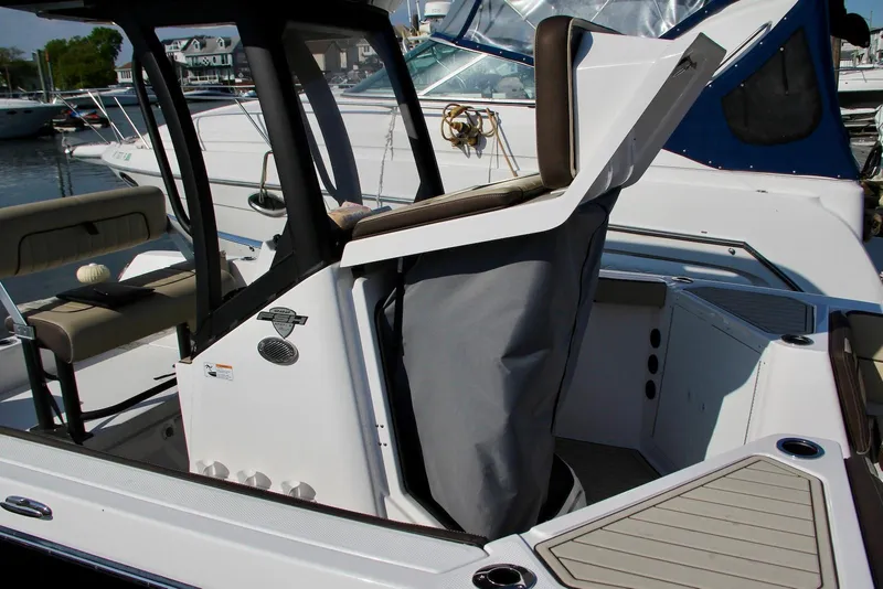 Slide: The Image of 2024 Yamaha Boats 222 FSH Sport E interior, showcasing seating and helm station at a marina. - 11