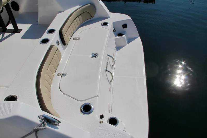 Slide: The Image of 2024 Yamaha Boats 222 FSH Sport E deck with seating and cup holders, reflecting sunlight on water. - 9