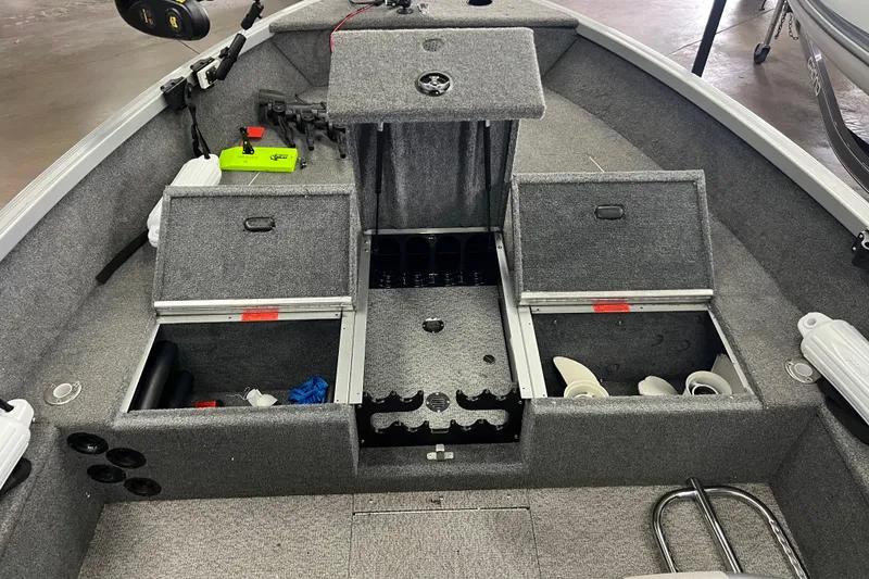 Slide: The Image of 2014 Alumacraft Competitor 165 Tiller boat interior with open storage compartments and fishing gear. - 18
