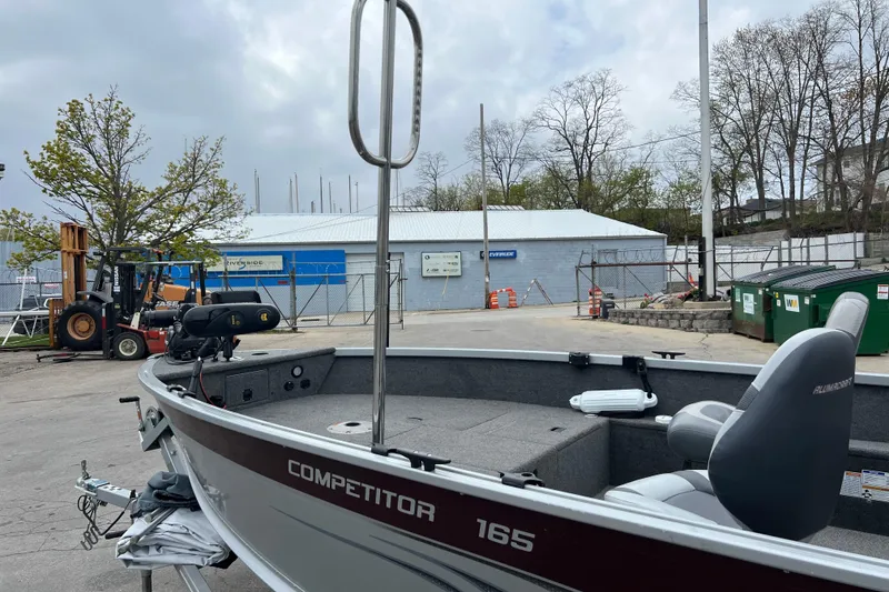 Slide: The Image of 2014 Alumacraft Competitor 165 Tiller boat parked near industrial area with forklift. - 23