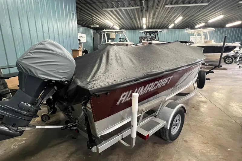 Slide: The Image of 2014 Alumacraft Competitor 165 Tiller boat with cover in indoor storage. - 27