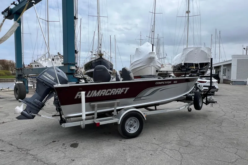 Slide: The Image of 2014 Alumacraft Competitor 165 Tiller boat on trailer, dockside with Yamaha outboard motor. - 4