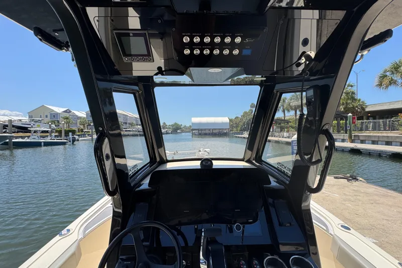 Slide: The Image of 2024 Scout 281 XSS boat cockpit view at marina, showcasing modern controls and waterfront scenery. - 12