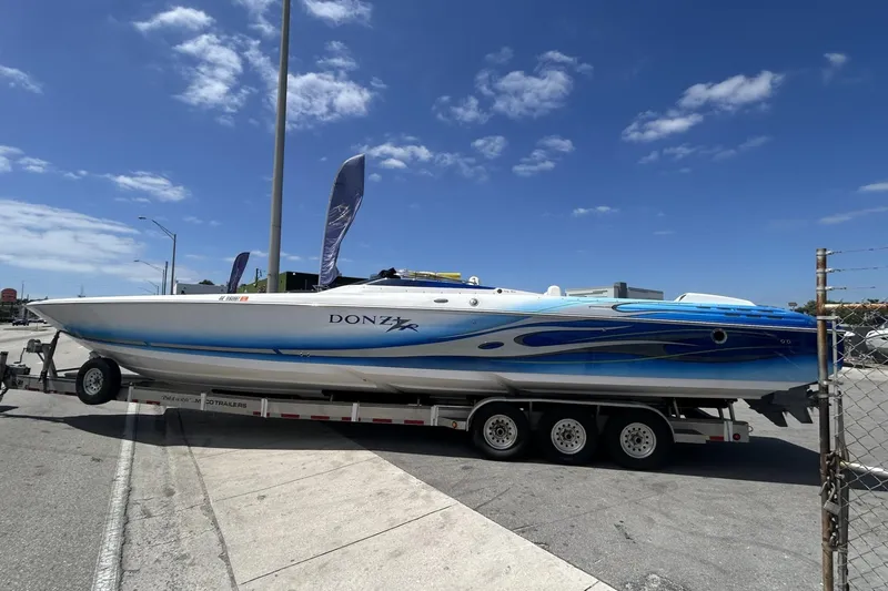 The Image of 2006 Donzi 43 ZR speedboat on trailer, featuring sleek blue and white design under clear sky. - 0