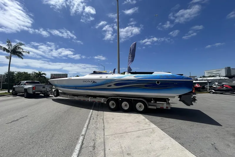 Slide: The Image of 2006 Donzi 43 ZR speedboat on trailer, parked on sunny street with palm trees. - 20