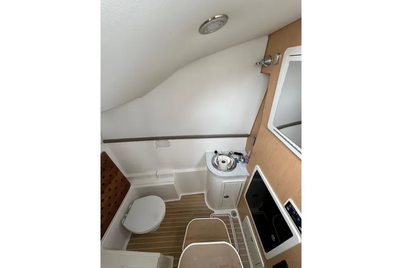 Slide: The Image of 2022 World Cat 325 DC boat bathroom interior with sink, toilet, and mirror. - 14