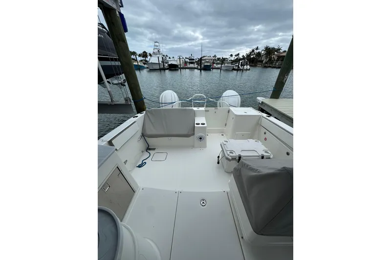 Slide: The Image of 2022 World Cat 325 DC boat docked at marina, showcasing spacious deck and seating area. - 17