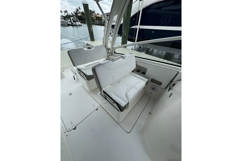 Slide: The Image of 2022 World Cat 325 DC boat interior with white seating, docked by the water. - 7