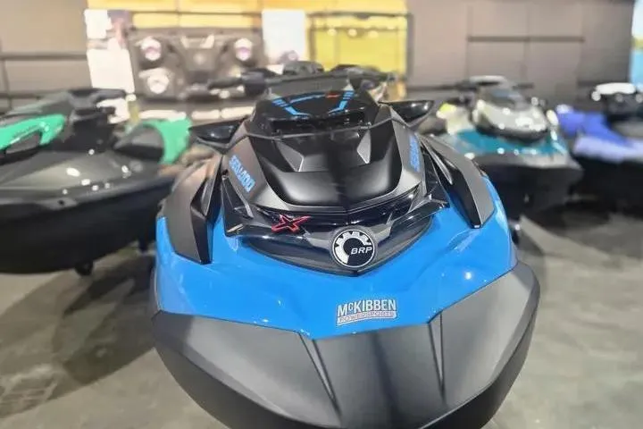 Slide: The Image of 2026 Sea-Doo RXT-X 325 jet ski in showroom, front view, blue and black design. - 13