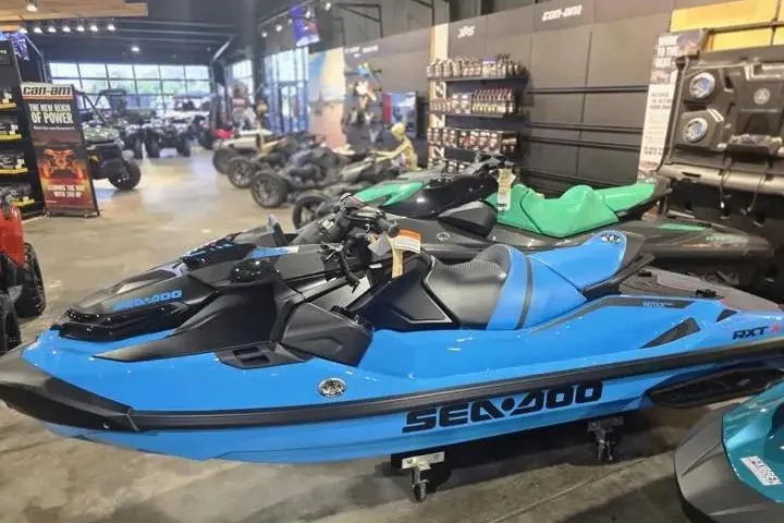 Slide: The Image of 2026 Sea-Doo RXT-X 325 jet ski in showroom, vibrant blue color, side view. - 5