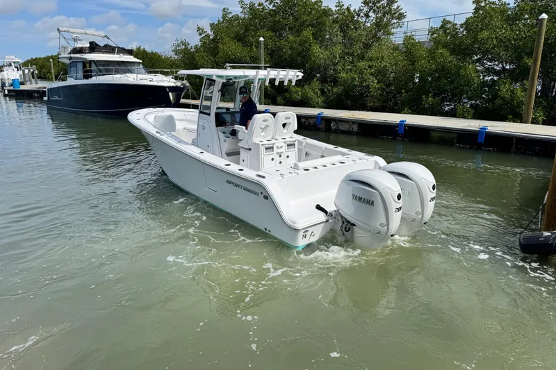 Slide: The Image of 2024 Sportsman Open 262 Center Console boat with twin Yamaha engines in a marina. - 10