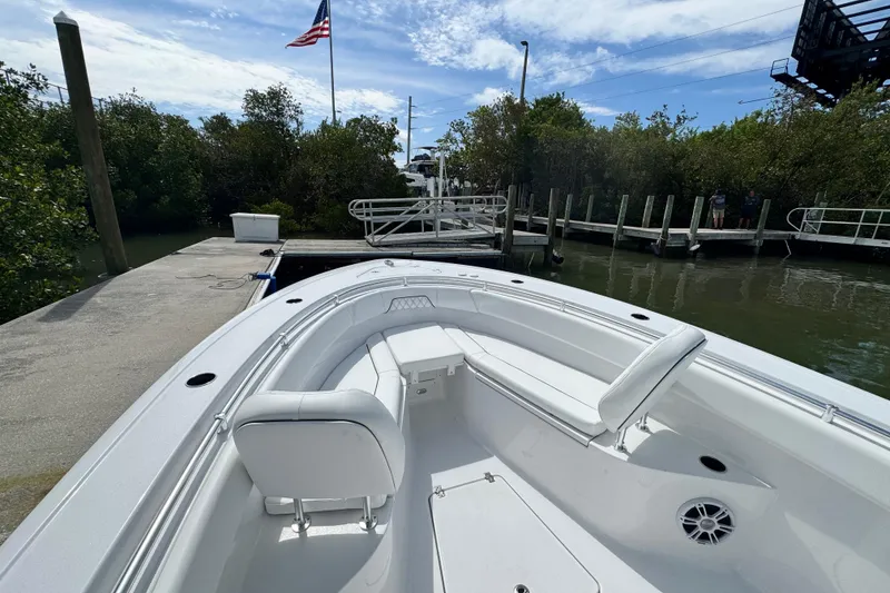 Slide: The Image of 2024 Sportsman Open 262 Center Console boat docked near lush greenery and American flag. - 12