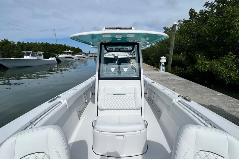 Slide: The Image of 2024 Sportsman Open 262 Center Console boat docked near lush greenery. - 13