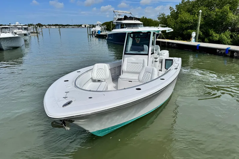 Slide: The Image of 2024 Sportsman Open 262 Center Console boat on calm water near a marina. - 2