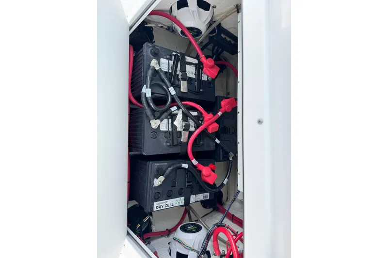 Slide: The Image of 2024 Sportsman Open 262 Center Console battery compartment with red cables and dry cell batteries. - 24