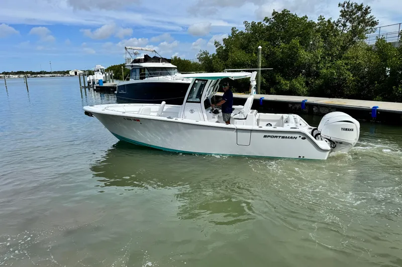 Slide: The Image of 2024 Sportsman Open 262 Center Console boat cruising near a dock with Yamaha engine. - 8