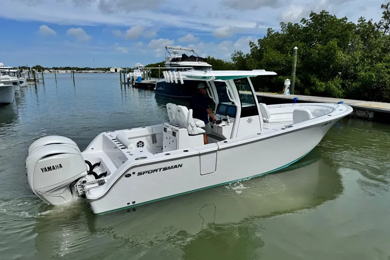 Slide: The Image of 2024 Sportsman Open 262 Center Console boat with Yamaha engines in a marina setting. - 9