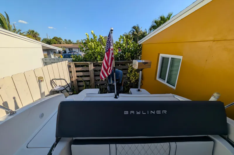 Slide: The Image of Bayliner DX 2000 boat, 2022 model, parked near a yellow house with an American flag. - 10