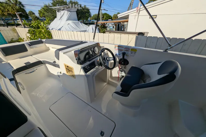 Slide: The Image of 2022 Bayliner DX 2000 boat interior with steering wheel and seating area. - 11