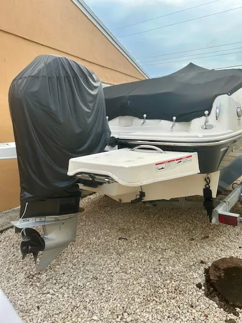 Slide: The Image of 2022 Bayliner DX2000 boat with covered motor, parked on gravel. - 18