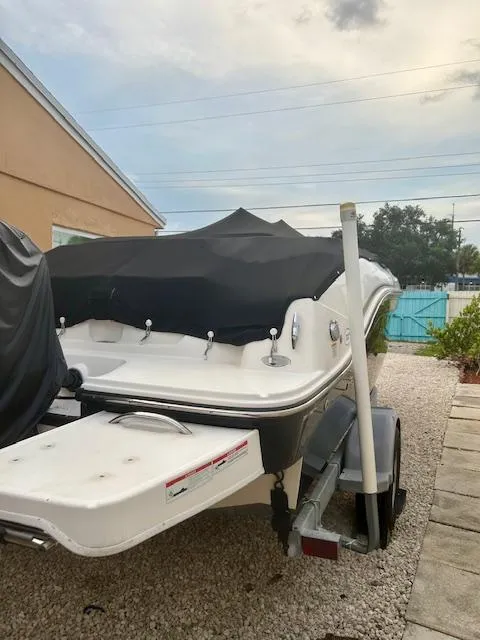 Slide: The Image of 2022 Bayliner DX2000 boat with cover, parked on a trailer in a residential area. - 19