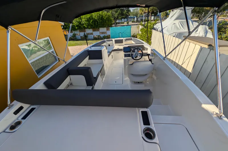 Slide: The Image of 2022 Bayliner DX 2000 boat interior with seating and steering wheel under canopy. - 2