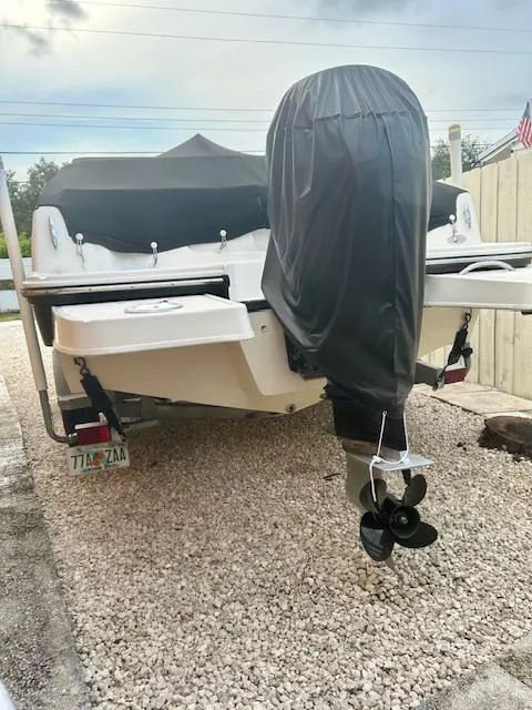 Slide: The Image of 2022 Bayliner DX2000 boat with covered outboard motor, parked on gravel. - 20