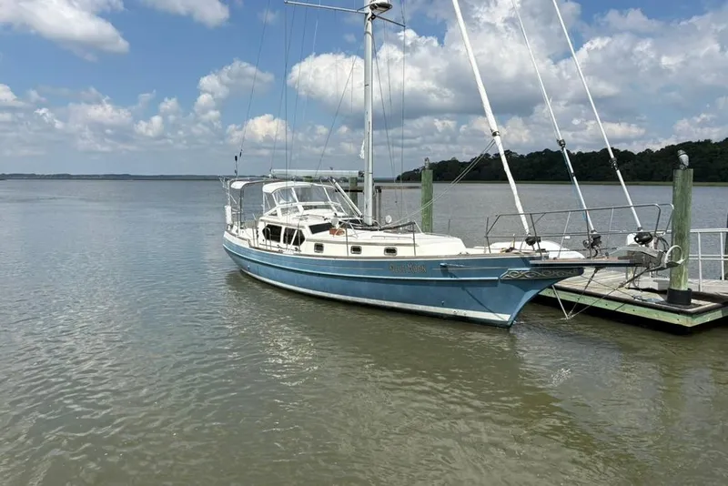 Slide: The Image of Sailboat Gozzard 41 RC, 2016 model, docked on a calm lake under a partly cloudy sky. - 2