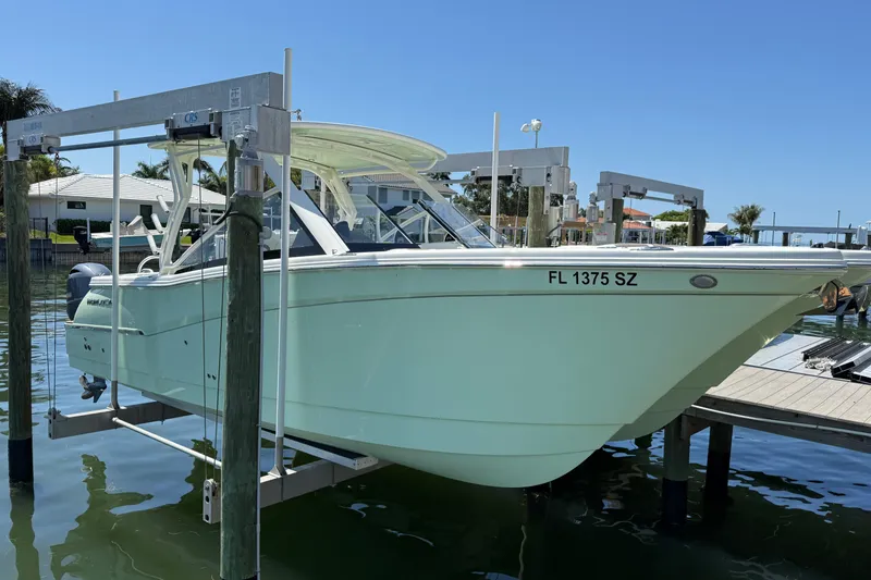 The Image of 2021 World Cat 280 DC-X boat on lift, docked in sunny marina. - 0
