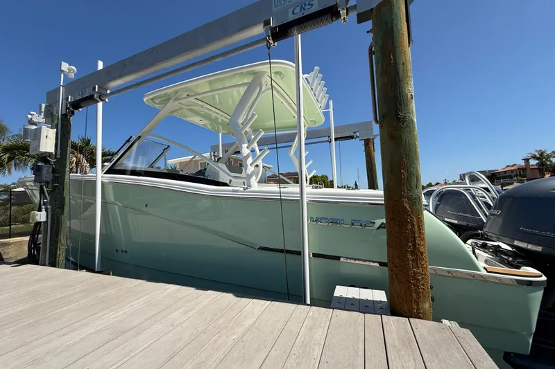 Slide: The Image of 2021 World Cat 280 DC-X boat on lift, docked under clear blue sky. - 2