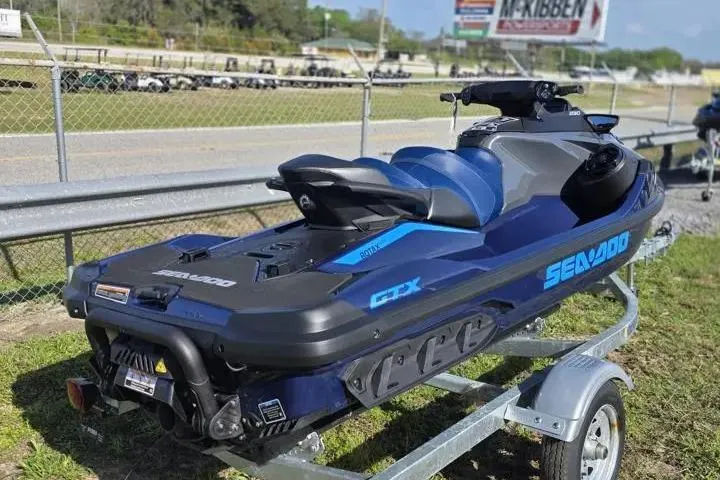 Slide: The Image of 2026 Sea-Doo GTX 230 jet ski on trailer, parked outdoors near a fence. - 6