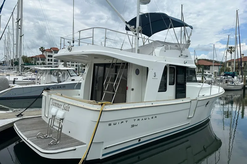 Slide: The Image of 2011 Beneteau Swift Trawler 34 Fly docked in a marina, side view. - 3