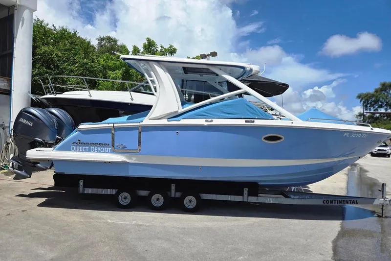Slide: The Image of 2022 Chaparral 280 OSX boat on trailer, blue hull, Yamaha engines, sunny day. - 27