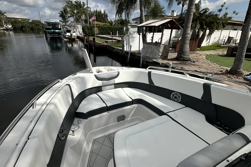 Slide: The Image of 2022 Chaparral 280 OSX boat with spacious seating, docked by a scenic canal. - 9